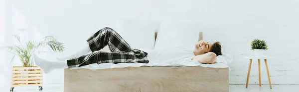 Plan panoramique de l'homme heureux couché sur le lit dans la chambre moderne — Photo de stock