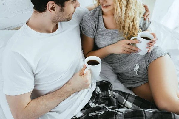 Vista recortada de hombre y mujer rubia sosteniendo tazas de café - foto de stock