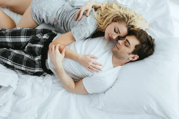 Vista superior do homem feliz e mulher abraçando enquanto deitado na cama — Fotografia de Stock