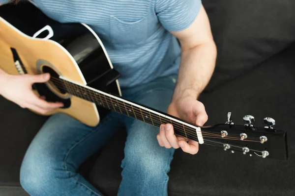 Vista cortada de músico tocando guitarra acústica em casa — Fotografia de Stock