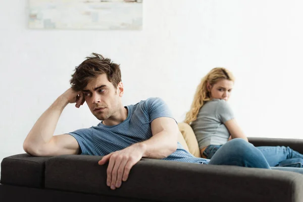 Селективное внимание расстроенного мужчины, сидящего рядом с блондинкой после ссоры — стоковое фото