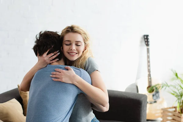 Feliz joven mujer sonriendo mientras abrazando novio en casa - foto de stock