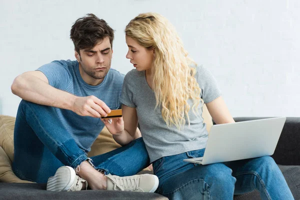 Блондинка сидит с ноутбуком рядом мужчина держит кредитную карту — стоковое фото