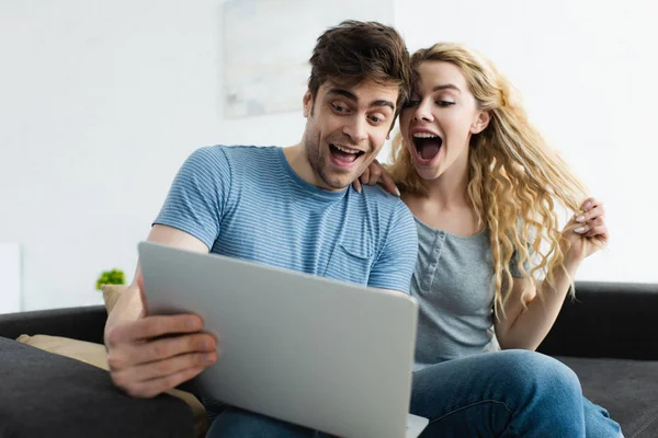 Cheerful man and happy blonde woman watching movie on laptop — Stock Photo