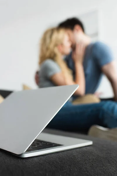 Foco seletivo de laptop perto de beijar homem e mulher — Fotografia de Stock