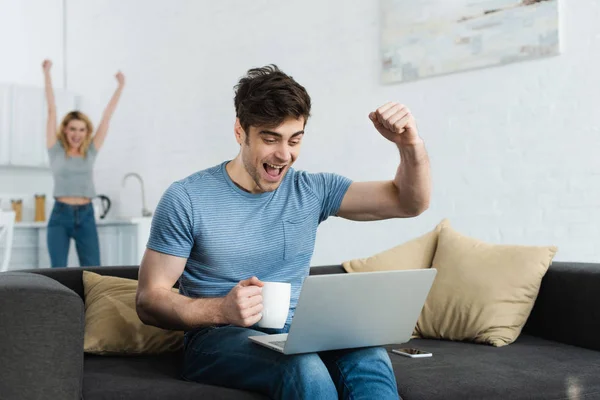 Selektiver Fokus des glücklichen Mannes, der den Triumph feiert, während er die Meisterschaft auf dem Laptop neben der Frau verfolgt — Stockfoto