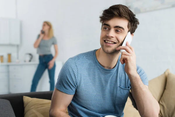 Selective focus of cheerful man talking on smartphone near woman — Stock Photo