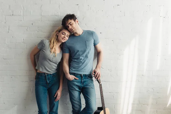 Handsome man standing with acoustic guitar near happy blonde girl — Stock Photo