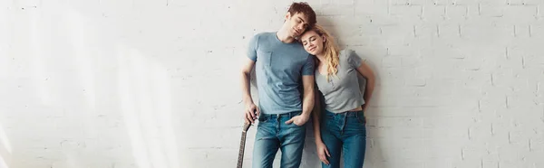 Panoramic shot of handsome man standing with acoustic guitar near happy blonde girl — Stock Photo