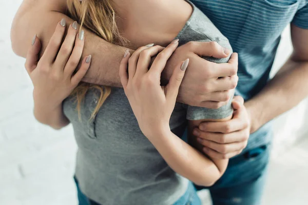 Vista recortada del hombre abrazando a la mujer joven en casa - foto de stock