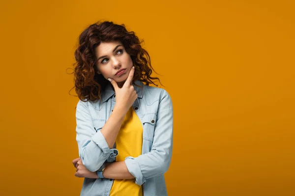 Pensive redhead woman thinking while standing on orange — Stock Photo