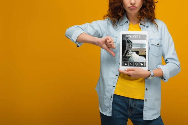 Vista cortada de mulher chateada segurando tablet digital com aplicativo de bilhetes na tela e mostrando o polegar para baixo na laranja — Fotografia de Stock