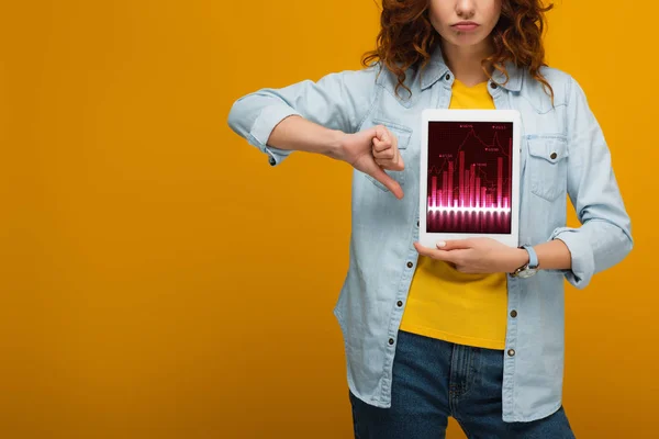 Vue recadrée de femme bouclée bouleversée tenant tablette numérique avec des graphiques à l'écran et montrant pouce vers le bas sur orange — Photo de stock