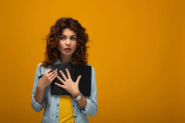 Sorpresa rossa giovane donna in possesso di notebook e penna arancione — Foto stock