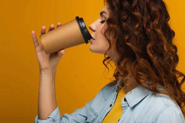 Curly redhead girl with closed eyes drinking coffee to go on orange — Stock Photo