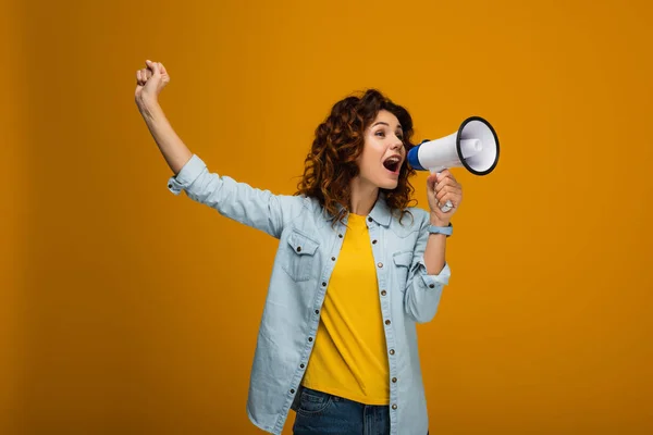 Rousse bouclée femme crier en mégaphone et geste sur orange — Photo de stock