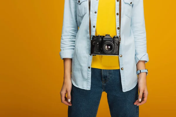 Cropped view of young woman standing with digital camera on orange — Stock Photo