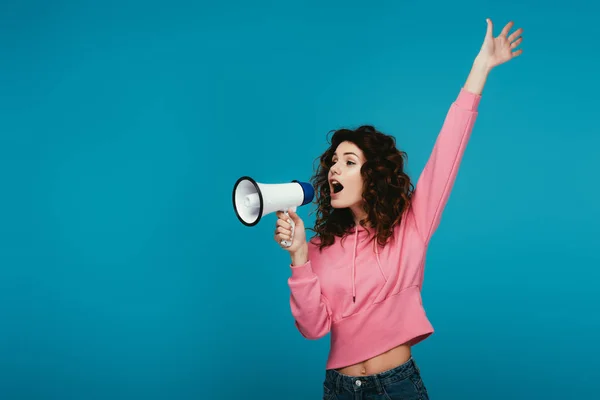 Atraente encaracolado ruiva menina gritando em megafone no azul — Fotografia de Stock