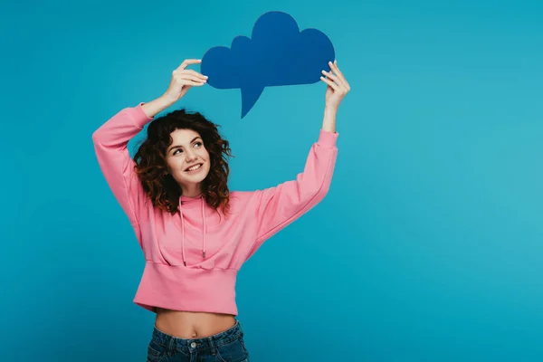 Happy curly redhead girl holding thought bubble on blue — Stock Photo