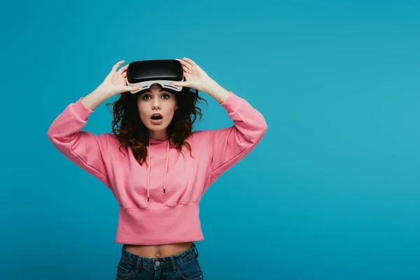 Überrascht lockiges Mädchen trägt Virtual-Reality-Headset auf blau — Stockfoto