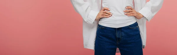 Panoramic shot of young woman standing with hands on hips isolated on pink — Stock Photo