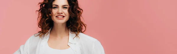 Tiro panorâmico de menina encaracolado feliz olhando para a câmera e sorrindo isolado em rosa — Fotografia de Stock