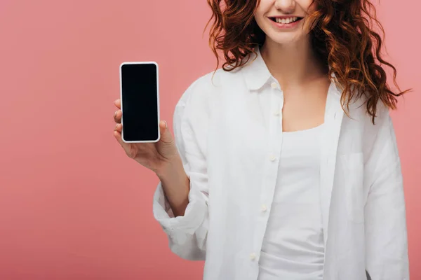 Vista recortada de niña alegre sosteniendo teléfono inteligente con pantalla en blanco en rosa - foto de stock