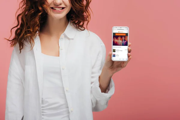 Cropped view of cheerful girl holding smartphone with soundcloud app on screen on pink — Stock Photo