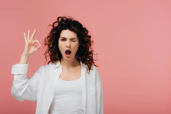 Curly young woman with red hair showing ok sign isolated on pink — Stock Photo