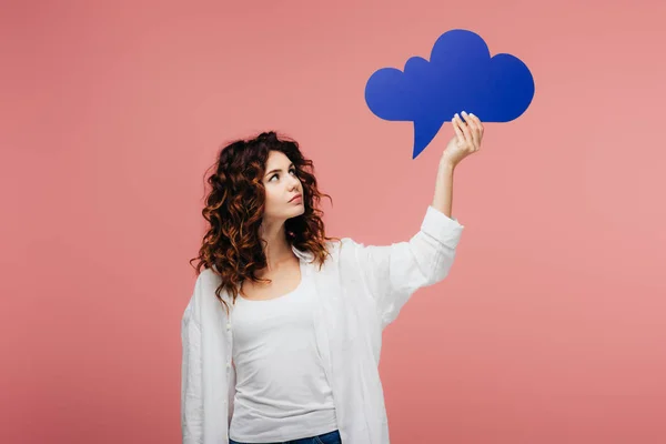 Attractive curly girl with red hair looking at blue thought bubble on pink — Stock Photo