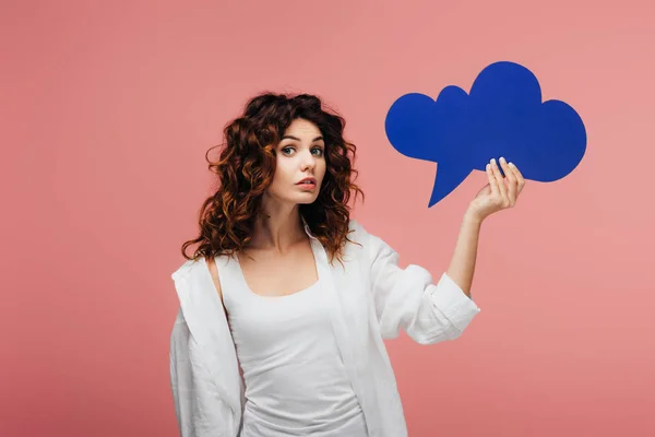 Attractive curly girl with red hair holding blue thought bubble on pink — Stock Photo