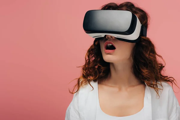 Sorprendida pelirroja rizada con auriculares de realidad virtual en rosa - foto de stock