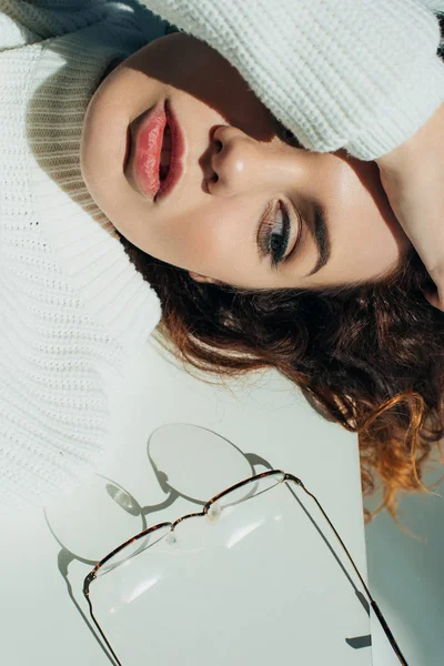 Top view of attractive curly redhead girl looking at glasses on white — Stock Photo