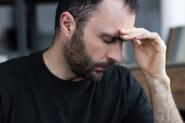 Triste bonito barbudo homem com olhos fechados segurando mão perto da testa — Fotografia de Stock