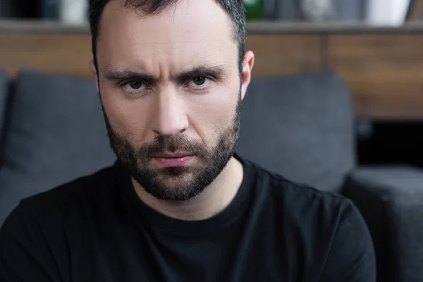 Serious handsome bearded man in black t-shirt looking at camera — Stock Photo