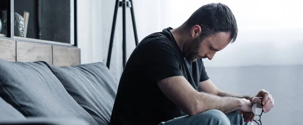 Панорамний знімок депресії з закритими очима, сидячи на сірому дивані вдома — стокове фото