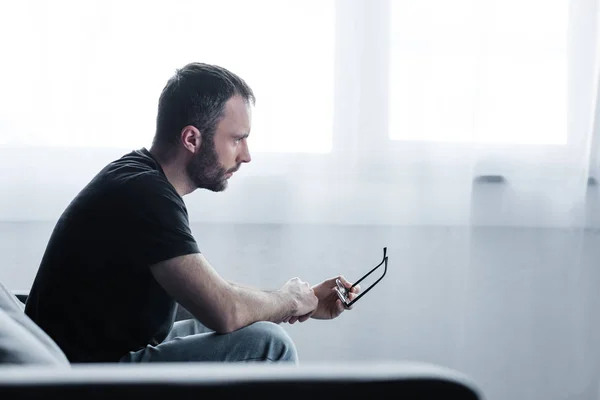 Depressiver Mann in schwarzem T-Shirt mit Brille und wegschauendem Blick — Stockfoto