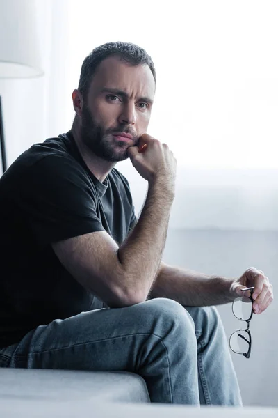 Schöner frustrierter Mann in schwarzem T-Shirt mit Brille und wegschauendem Blick — Stockfoto