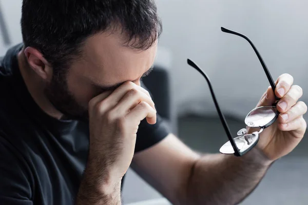 Messa a fuoco selettiva dell'uomo adulto con mano vicino agli occhi che tengono gli occhiali — Foto stock