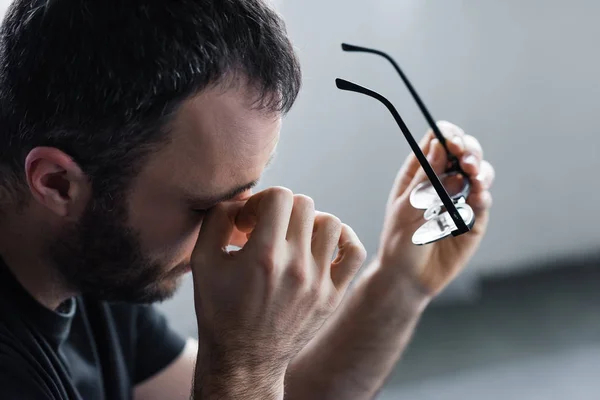 Selective focus of upset man with hand near eyes holding glasses — Stock Photo