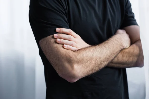 Erwachsener Mann in schwarzem T-Shirt steht mit verschränkten Armen am Fenster — Stockfoto