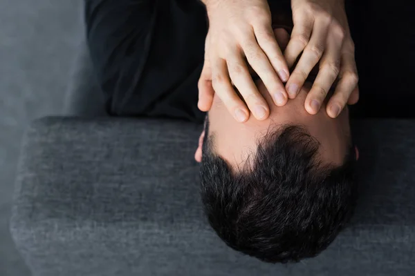 Vista aérea del hombre deprimido de pelo corto cogido de la mano en la cara — Stock Photo