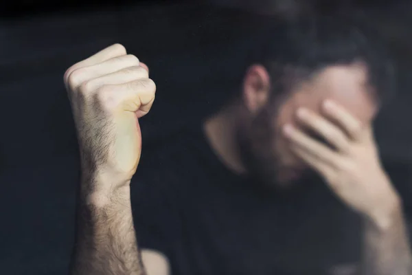 Selective focus of depressed man with hand on face holding hand in fist — Stock Photo
