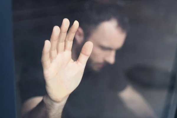 Selective focus of frustrated man holding hand on window glass — Stock Photo