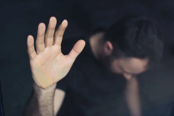 Selective focus of depressed man holding hand on window glass — Stock Photo