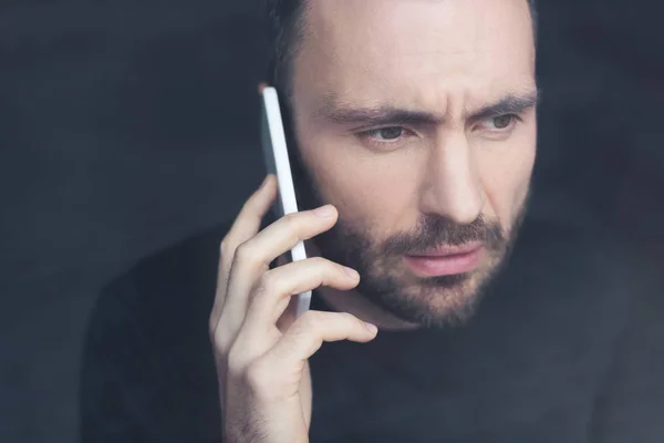 Trauriger, gutaussehender bärtiger Mann mit Smartphone und wegschauendem Blick — Stockfoto