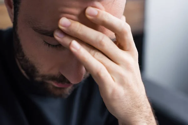 Foyer sélectif de l'homme bouleversé tenant la main sur le front avec les yeux fermés — Photo de stock