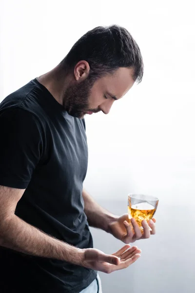 Депрессивный бородатый мужчина стоит с закрытыми глазами и держит стакан виски — стоковое фото