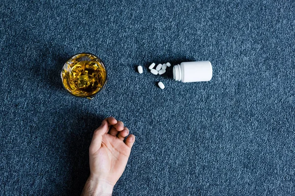 Ansicht der männlichen Hand in der Nähe von Behältern mit Pillen in der Nähe von Whiskey und Behältern mit Pillen — Stockfoto