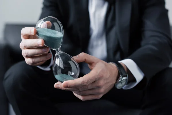 Cropped view of sitting man in suit holding hourglass — Stock Photo